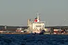 Stor passagerarfärja vid kajen i en hamn med mörkt vatten och byggnader i bakgrunden.