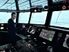 Joakim Killman står på bryggan vid ett fartygs navigationspaneler med havet synligt genom stora fönster.