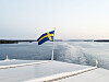 Svensk flagga på ett fartyg med lugnt vatten och horisont i bakgrunden.