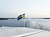 Svensk flagga på ett fartyg med lugnt vatten och horisont i bakgrunden.