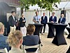 Fem personer deltar i en paneldiskussion utomhus med publik sittande framför.