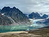 Turkos glaciärsjö med berg och is i bakgrunden.