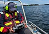 Person i arbetsbåt hanterar drönare.