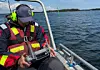 Person i arbetsbåt hanterar drönare.