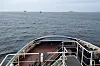 Bogserbåt i förgrunden, tankfartyg och bogserbåt i horisonten.