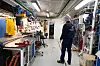 Tekniker går i en ljus verkstad med arbetsbänkar, verktyg och maskiner.